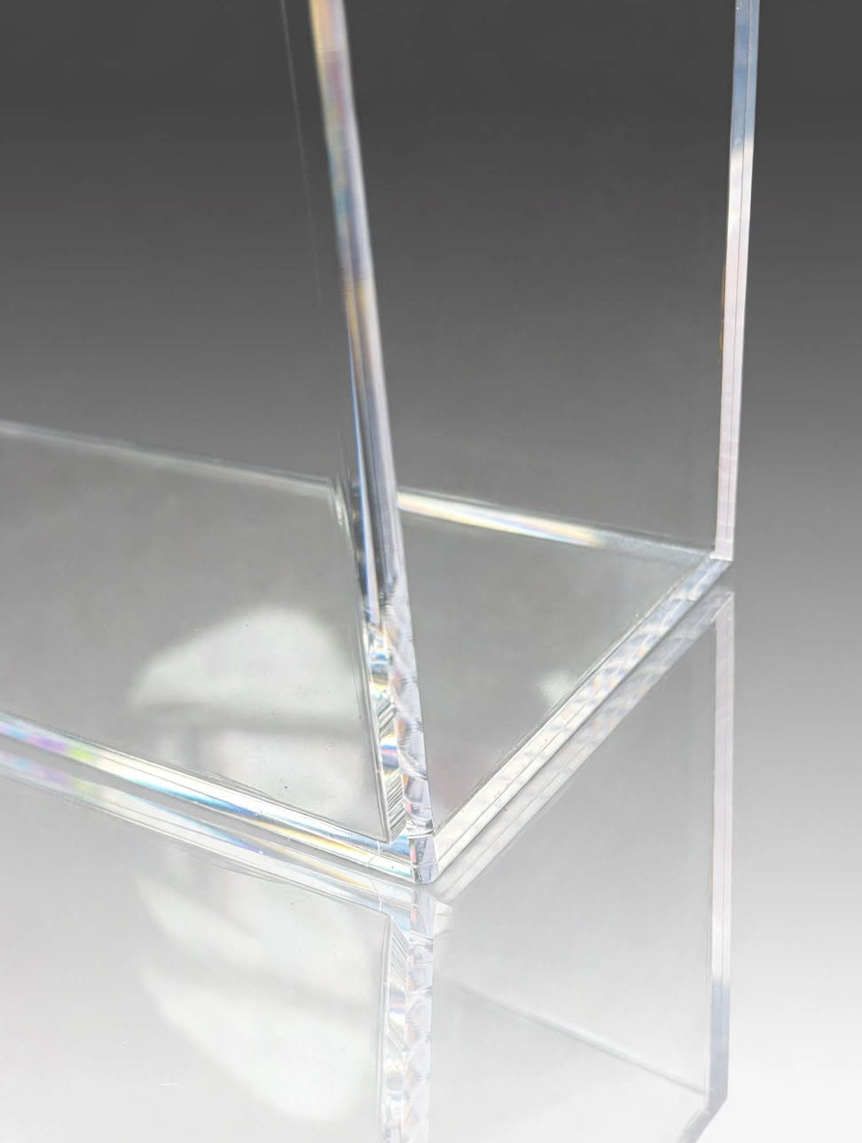 Clear acrylic display block with transparent edges and a smooth reflective surface, shown on a light gray gradient background.
