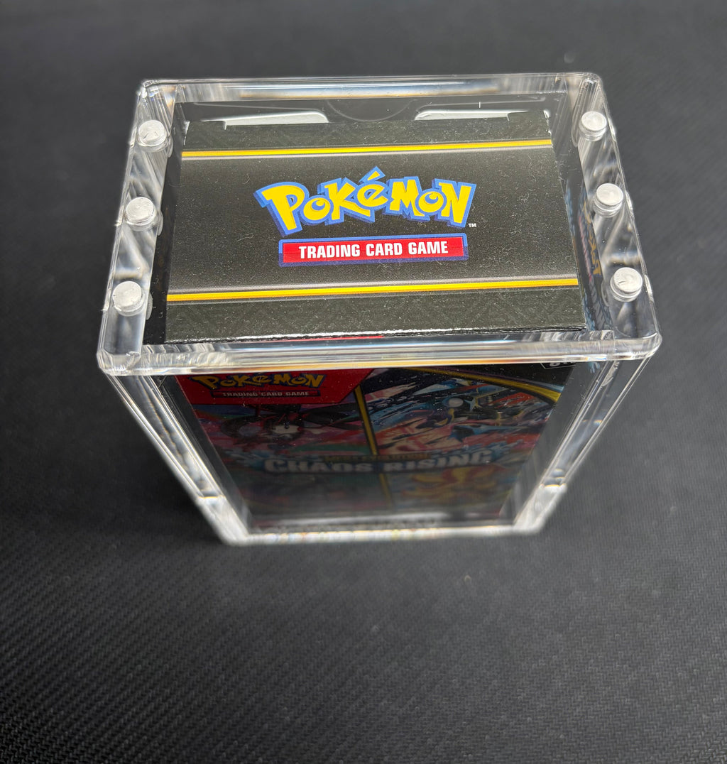 A clear acrylic display box containing a Pokémon Trading Card Game deck, photographed on a dark textured surface. The Pokémon logo is clearly visible on the top of the deck.