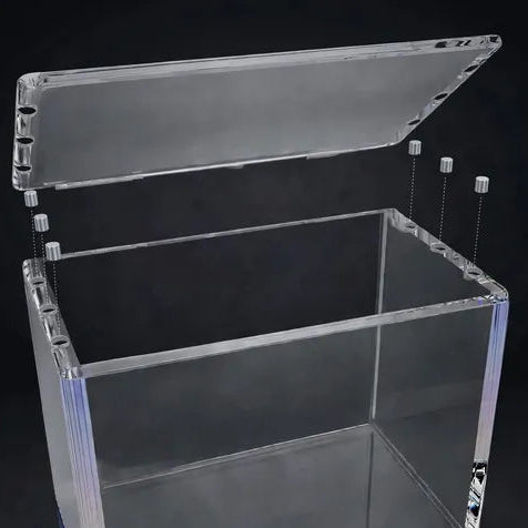 Clear acrylic storage box with a hinged lid, shown open on a dark reflective background. The brand name 'CRALGUARD' is printed on the bottom edge of the base.